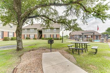 A tree with a mailbox in front of apartment buildings.